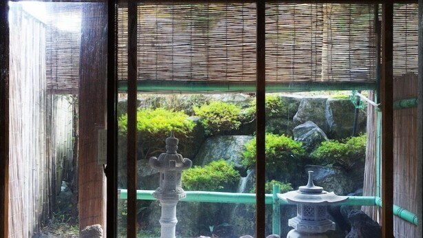 Ein traditioneller japanischer Garten mit Steinfluren und einem Bambuszaun.