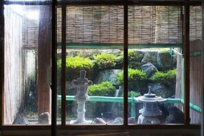 A traditional Japanese garden with stone lanterns and a bamboo fence. - Sanmalte Hotel (Hakuba)