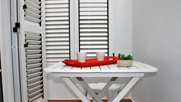A white table with a red tray, two white cups, and a small potted plant.