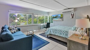 Een moderne slaapkamer met een bed, bureau en een bank. Grote ramen bieden uitzicht op het landschap.