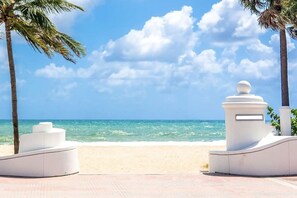 Une plage avec des structures blanches, des palmiers et un ciel bleu azur.