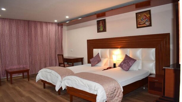 A double bed with a wooden headboard, two bedside tables, a chair, and a curtain. - Hotel Sujata (Gaya)