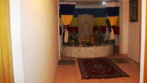 A hallway leading to a room with a Buddha statue, a red carpet, and a painting on the wall. - Hotel Sujata (Gaya)