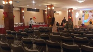 A banquet hall with rows of chairs, a stage with draped curtains, and a buffet table. - Hotel Sujata (Gaya)