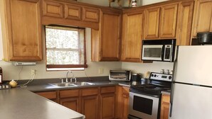 A kitchen with wooden cabinets, a microwave, a stove, and a refrigerator.