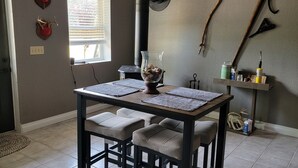 A dining area with a dark wooden table, four cushioned chairs, and a hanging pendant light.