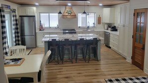 A modern kitchen with a central island, white cabinetry, and a wooden ceiling. - Walking distance to four-season ski and golf resort Crystal Mountain (Thompsonville)