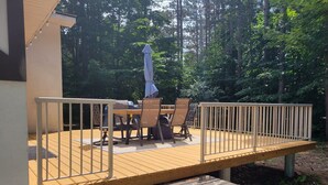 A wooden deck with a table and chairs, a covered grill, and a railing. - Walking distance to four-season ski and golf resort Crystal Mountain (Thompsonville)