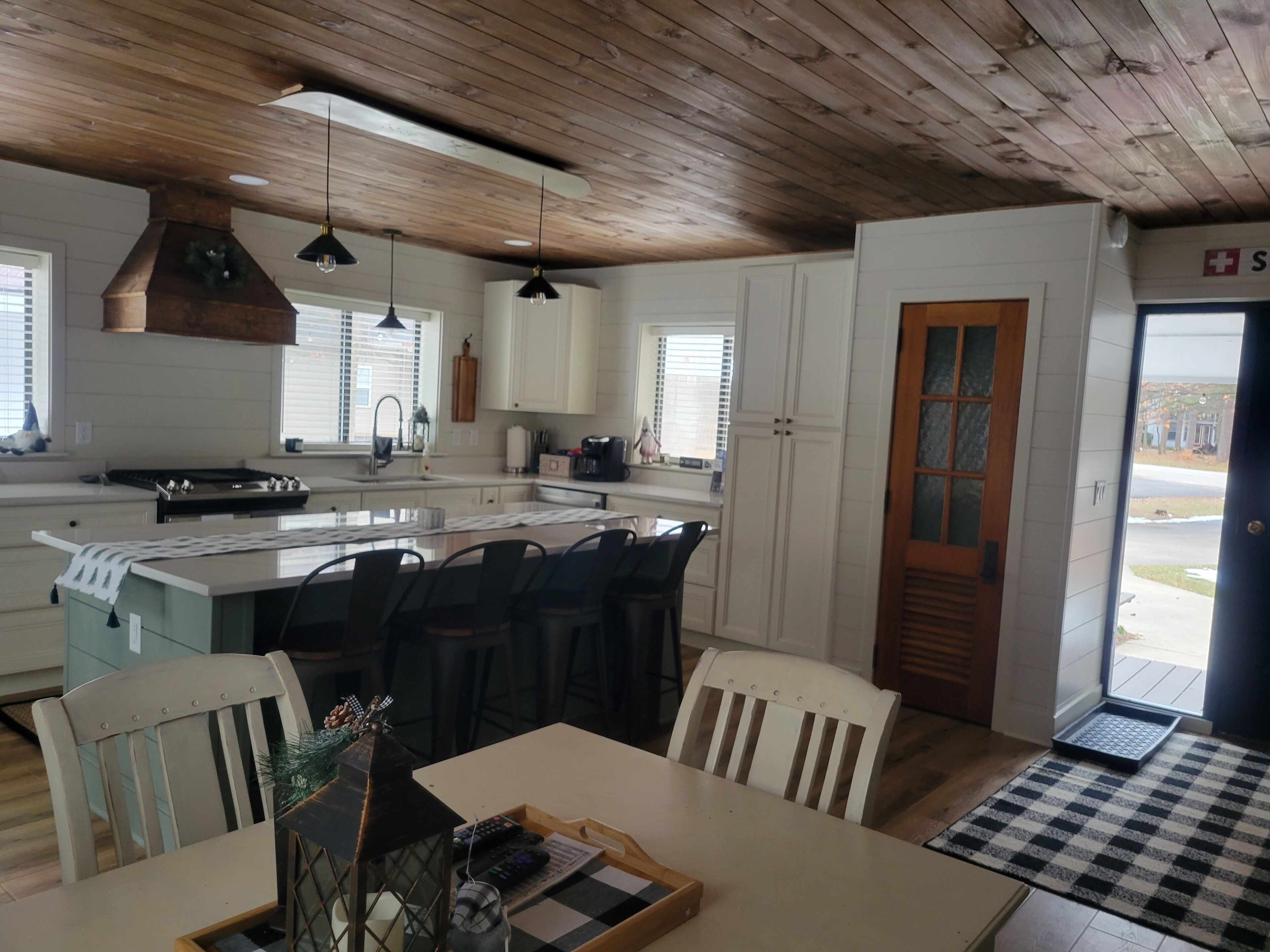 Una cocina moderna con una isla central, armarios blancos y techo de madera.