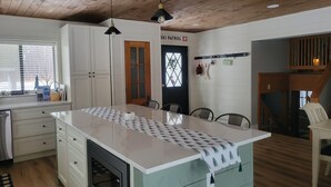 A modern kitchen with a central island, wooden ceiling, and a ski patrol sign on the wall. - Walking distance to four-season ski and golf resort Crystal Mountain (Thompsonville)