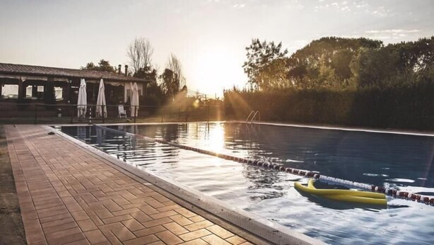 A swimming pool with a brick deck, a lifeguard stand, and a yellow float. - Al Poggio dei Papi (Citta della Pieve)