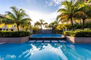 Une piscine entourée de palmiers et bordée d’un mur de pierre.