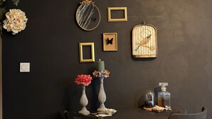 A round dining table with chairs, a vase with flowers, wall-mounted decorative items, and a birdcage. - Studio Nature Avec vue sur le Château (Caen)