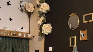 A bar area with a wine bottle, glasses, and a vase with flowers. - Studio Nature Avec vue sur le Château (Caen)