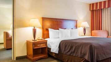 A hotel room with a large bed, two bedside tables with lamps, a chair, and a door.