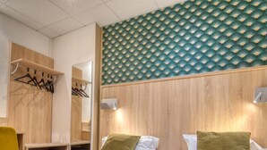 Habitación de hotel con dos camas, cabecero de madera, un espejo, un escritorio y una silla.