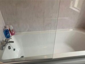 Bathroom features a large bathtub with a single faucet and drain.