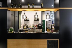 A modern bar area with a black countertop, multiple bottles, glasses, and a digital clock. - Central Lodge (Rome)