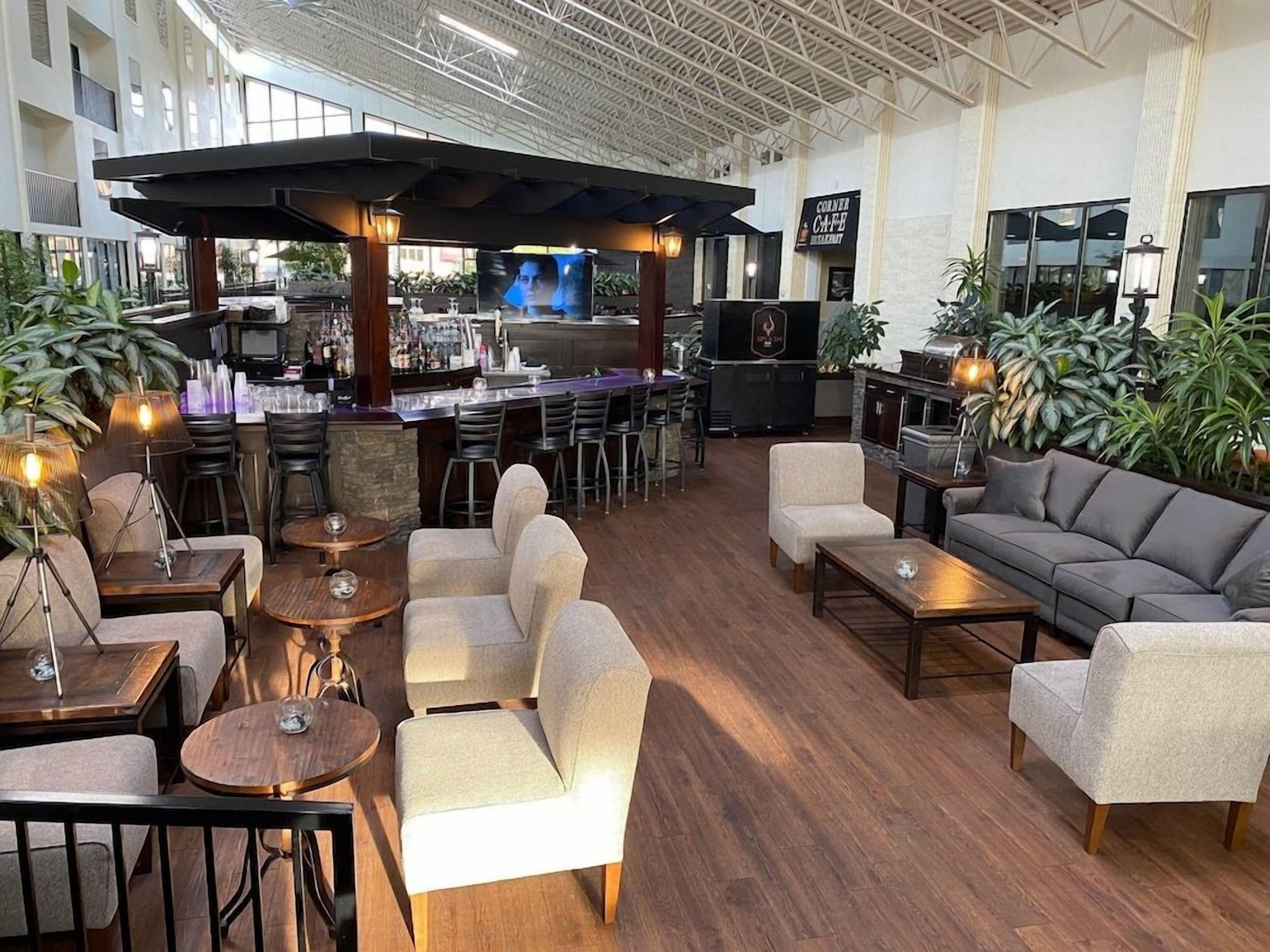 Een ruime lounge met een bar, zitgedeeltes en een televisiescherm.