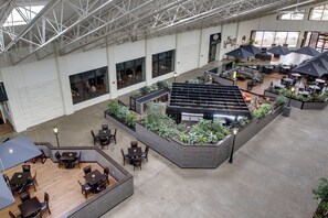 A spacious indoor area with multiple seating arrangements, including tables and chairs, and a central garden area with plants. - Doubletree by Hilton Quincy (Quincy)