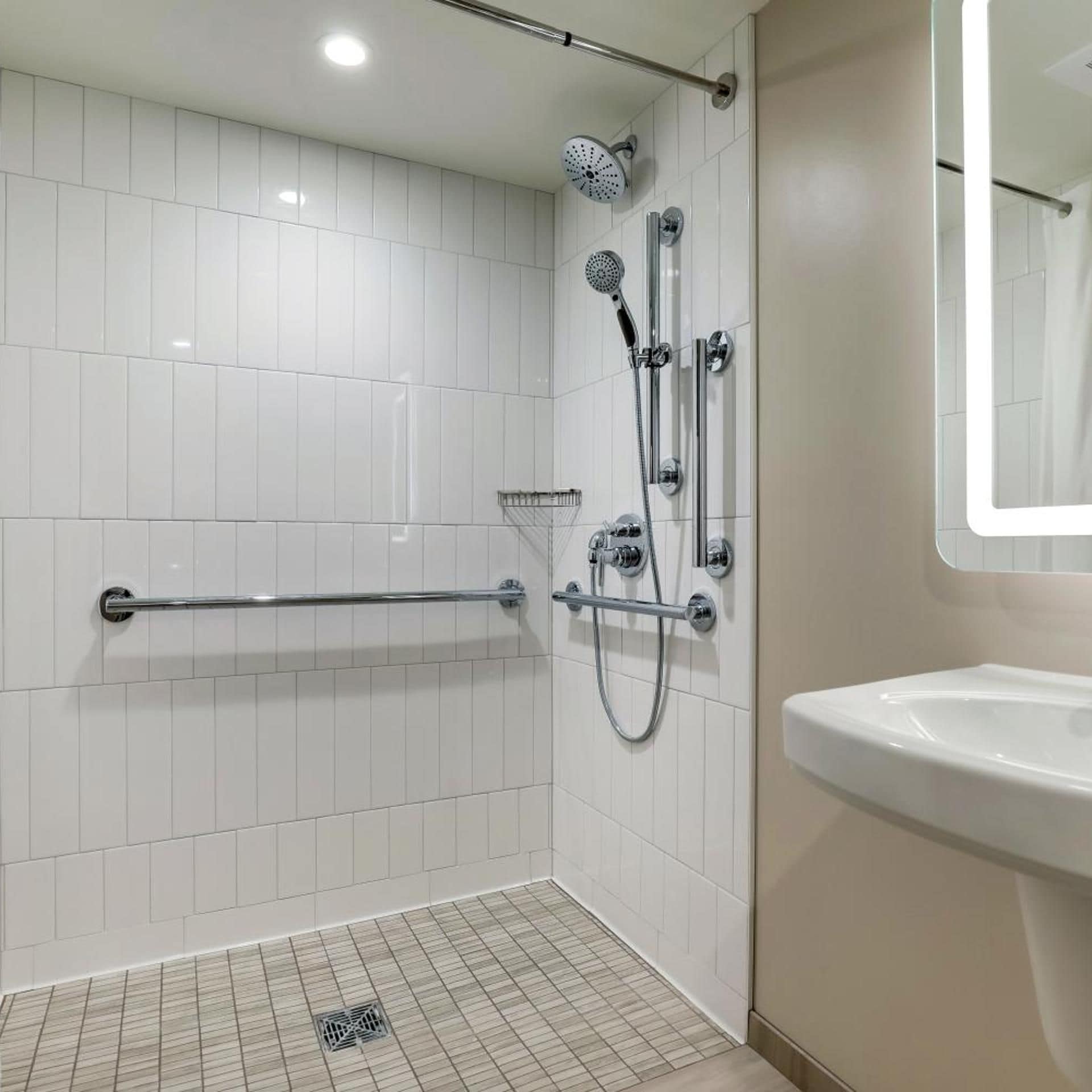 Um banheiro moderno com azulejos brancos e chuveiro com chuveiro manual.