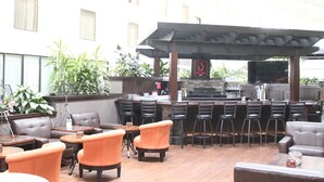 Zona de bar al aire libre con asientos y una parrilla.