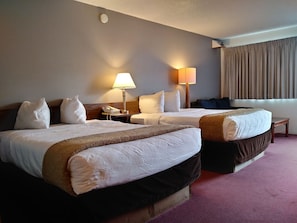 A hotel room with two beds, a bedside table with a lamp, a telephone, and a window with curtains. - University Inn (Corvallis)