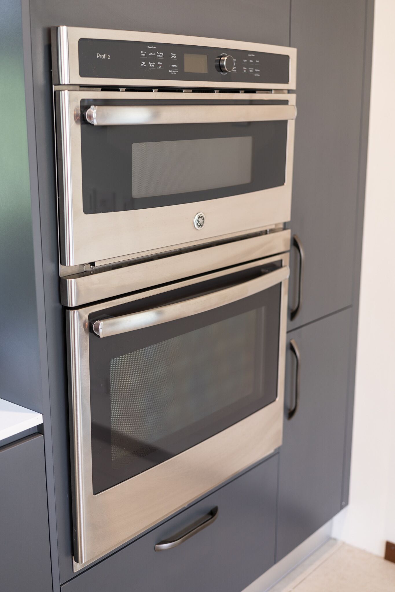 A stainless steel double oven built into a grey cabinet.