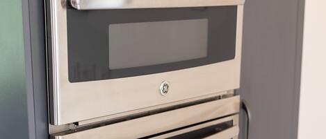 A stainless steel double oven built into a grey cabinet.