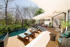 A modern outdoor pool area with lounge chairs, a hot tub, and a wooden deck.