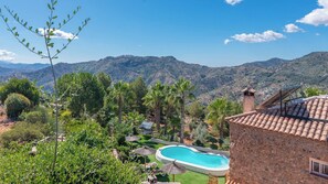 Una piscina rodeada de vegetación exuberante y montañas al fondo.