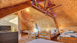 An attic bedroom with wooden beams, two beds, a dresser, and string lights. - For a vacation in the heart of the magic of Brocéliande, come and stay at Le Libert (Mauron)
