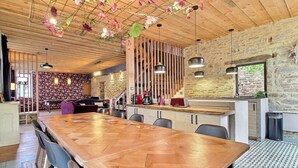 A spacious dining area with a long wooden table, stone walls, and hanging floral decorations. - For a vacation in the heart of the magic of Brocéliande, come and stay at Le Libert (Mauron)
