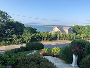 A residential area with a house overlooking a body of water, surrounded by lush greenery and a well-maintained garden.