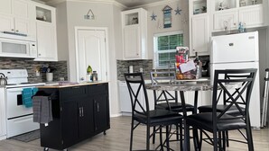 A modern kitchen with white cabinets, a black island, and a marble countertop. - Cooper's Cottage (Camano)