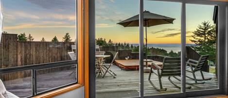 A room with a large sliding glass door leading to an outdoor deck with a view of the sunset.