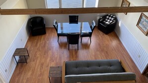 A loft-style room with a high ceiling, a dining table with chairs, a sofa, and a bench. - Near Munising snowmobile trails. Ride out from the property  (Munising)