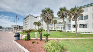 A hotel with a modern design, featuring a central courtyard with palm trees and a grassy area. - Daytona Beach Condo w/ Ocean-View Balcony! (Daytona Beach)