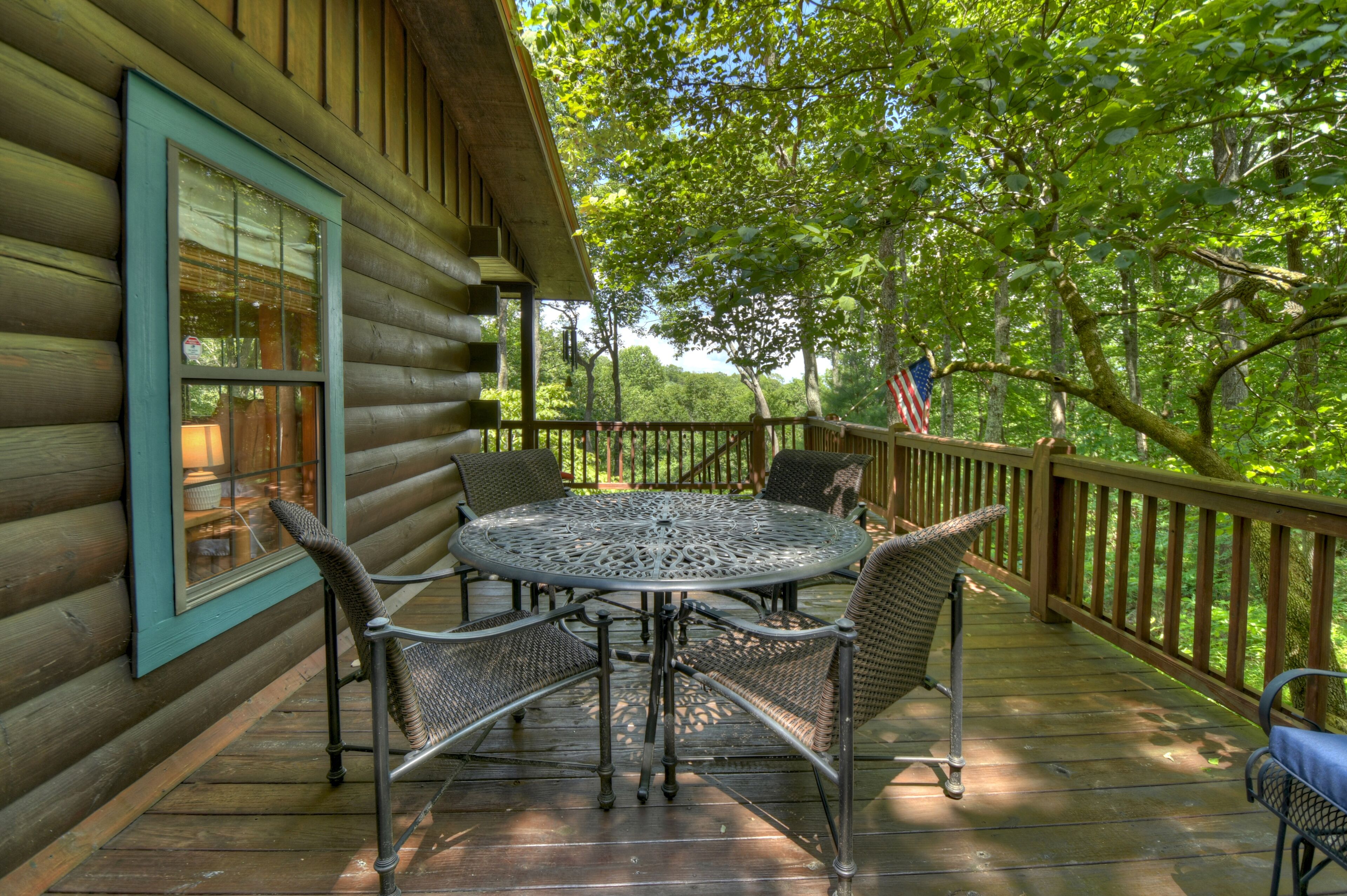 A wooden cabin with a deck, a round table, and four wicker chairs.