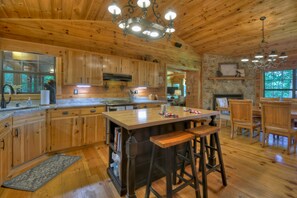 L’intérieur d’un chalet en bois comprend une grande cuisine, des tabourets de bar et une cheminée.