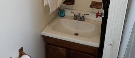 A bathroom with a sink, mirror, towel rack, and toilet paper holder.