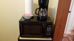 Un espace cuisine compact comprenant un four à micro-ondes, une machine à café et un petit placard.