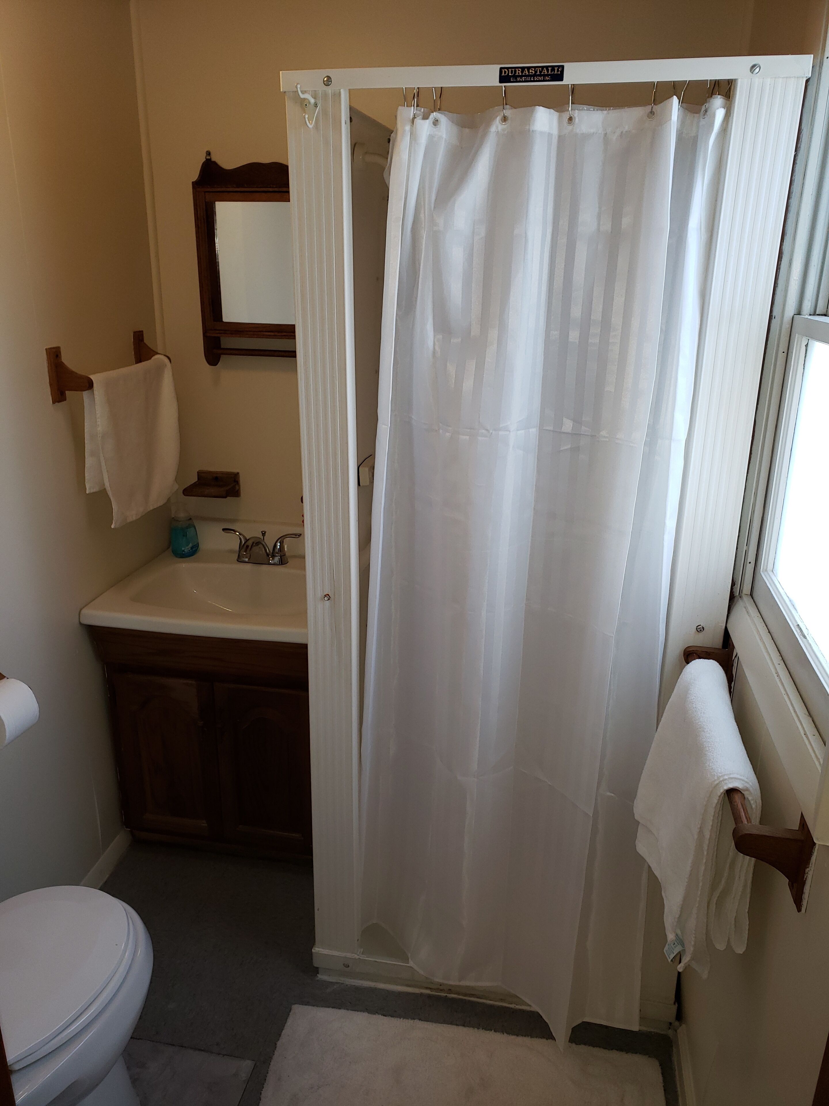 A bathroom with a shower curtain, a toilet, a sink, and a mirror.