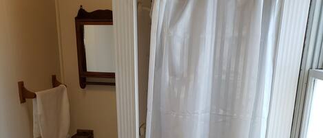 A bathroom with a shower curtain, a toilet, a sink, and a mirror.