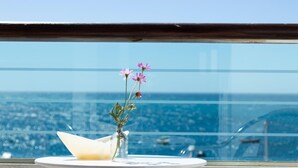 A balcony with a table, a vase with flowers, and a view of the ocean. - Hotel Embarcadero De Calahonda (Motril)