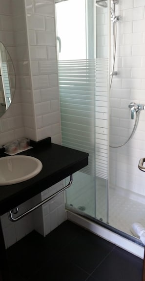 A bathroom with a glass-enclosed shower, a white sink, and a mirror. - Hotel Embarcadero De Calahonda (Motril)