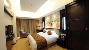A hotel room with a large bed, a desk, a chair, a TV, and a wardrobe. - Hengshan Beijiao Hotel (Shanghai)