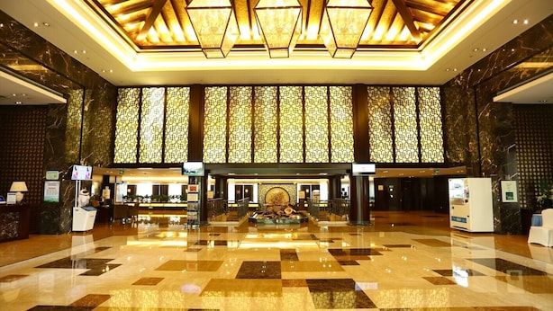 A spacious lobby with a checkered floor, a central fountain, and a reception desk. - Hengshan Beijiao Hotel (Shanghai)