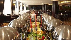 A buffet setup with multiple food stations, a bar area, and seating arrangements in a spacious dining area. - Hengshan Beijiao Hotel (Shanghai)
