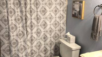 Een bad/douchecombinatie, een haardroger, handdoeken, zeep